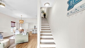 A modern interior with a staircase, a dining area, and a living room. - Palm Grove at Sago Sands Unit A (Santa Rosa Beach)