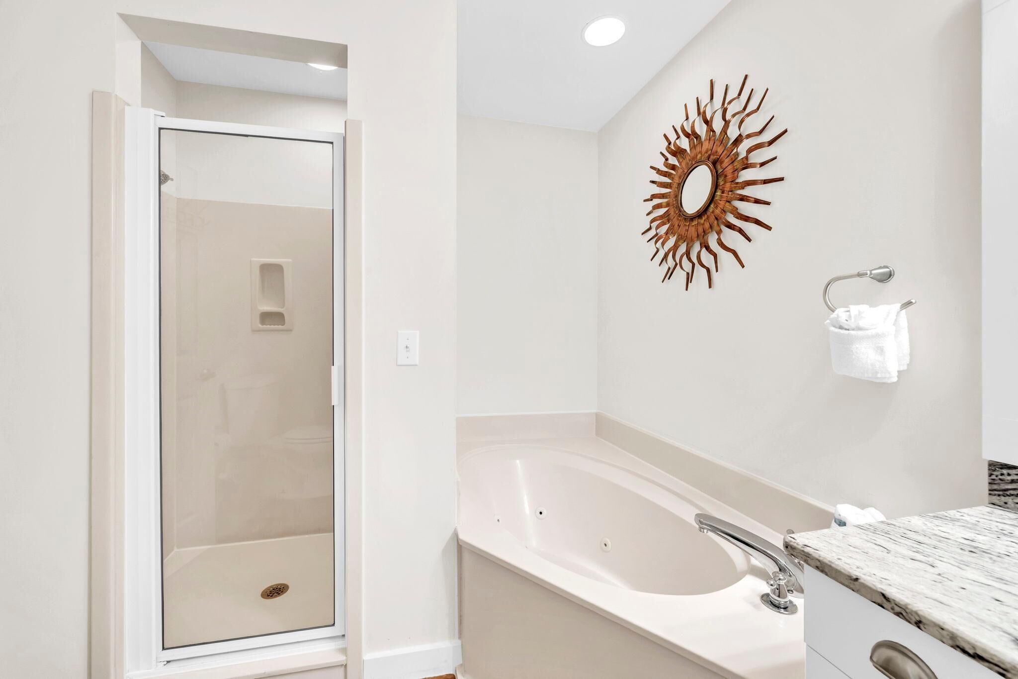Une salle de bain moderne avec une douche à parois de verre, une baignoire sur pieds et un grand miroir rond fixé au mur.
