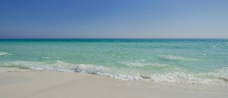 Ein Strand mit klarem türkisblauem Wasser und weißem Sand.