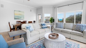 A spacious living room with a white sofa, a dining table, and a ceiling fan. - Legacy 104 (Santa Rosa Beach)