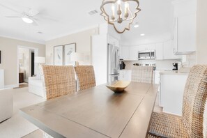 A modern kitchen with white cabinets, a stainless steel refrigerator, and a microwave. - Double Down (Santa Rosa Beach)