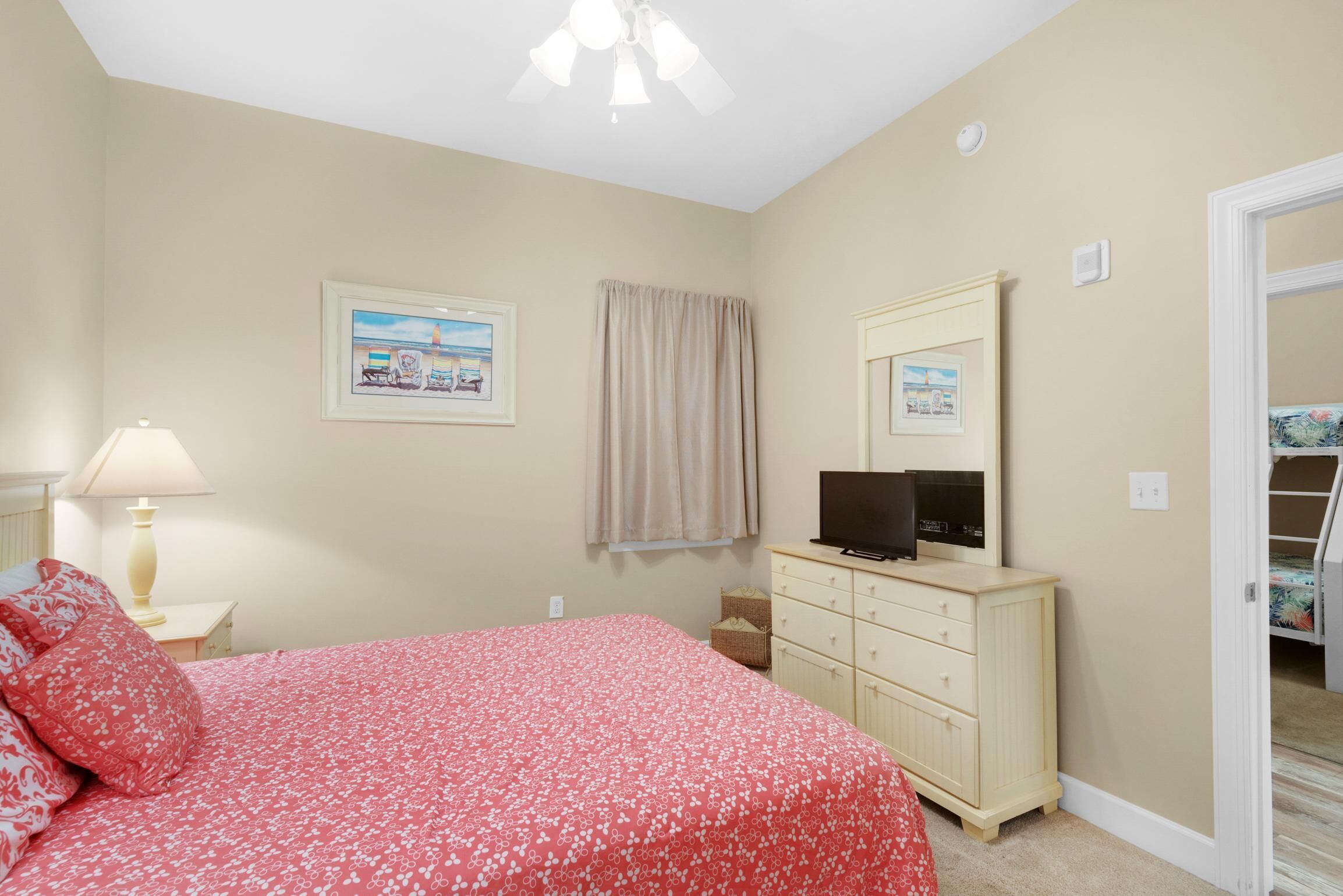 A bedroom with a bed, dresser, lamp, and a painting on the wall.