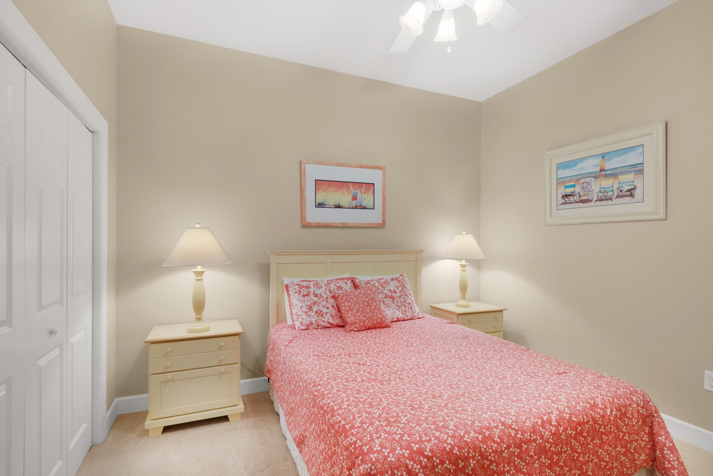 A bedroom with a bed, two bedside tables, a nightstand, a door, and two wall-mounted lamps.