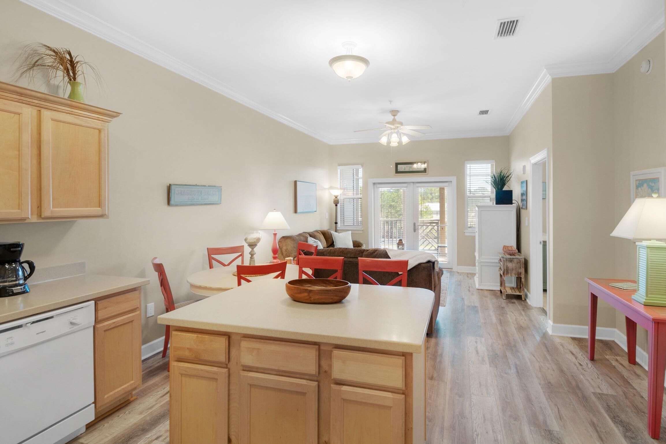 A spacious kitchen with wooden cabinets, a central island, and a dining area with red chairs.