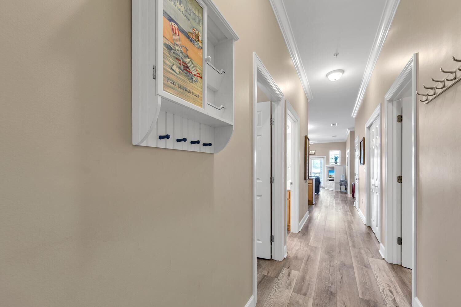 Un couloir doté d’un plancher en bois, de murs blancs et de portes de part et d’autre.