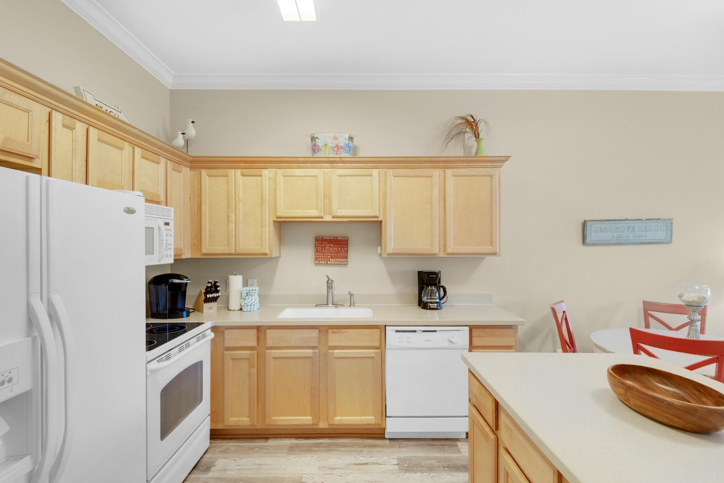 Une cuisine moderne avec des meubles en bois, un réfrigérateur blanc, une cuisinière, un lave-vaisselle et une machine à café.