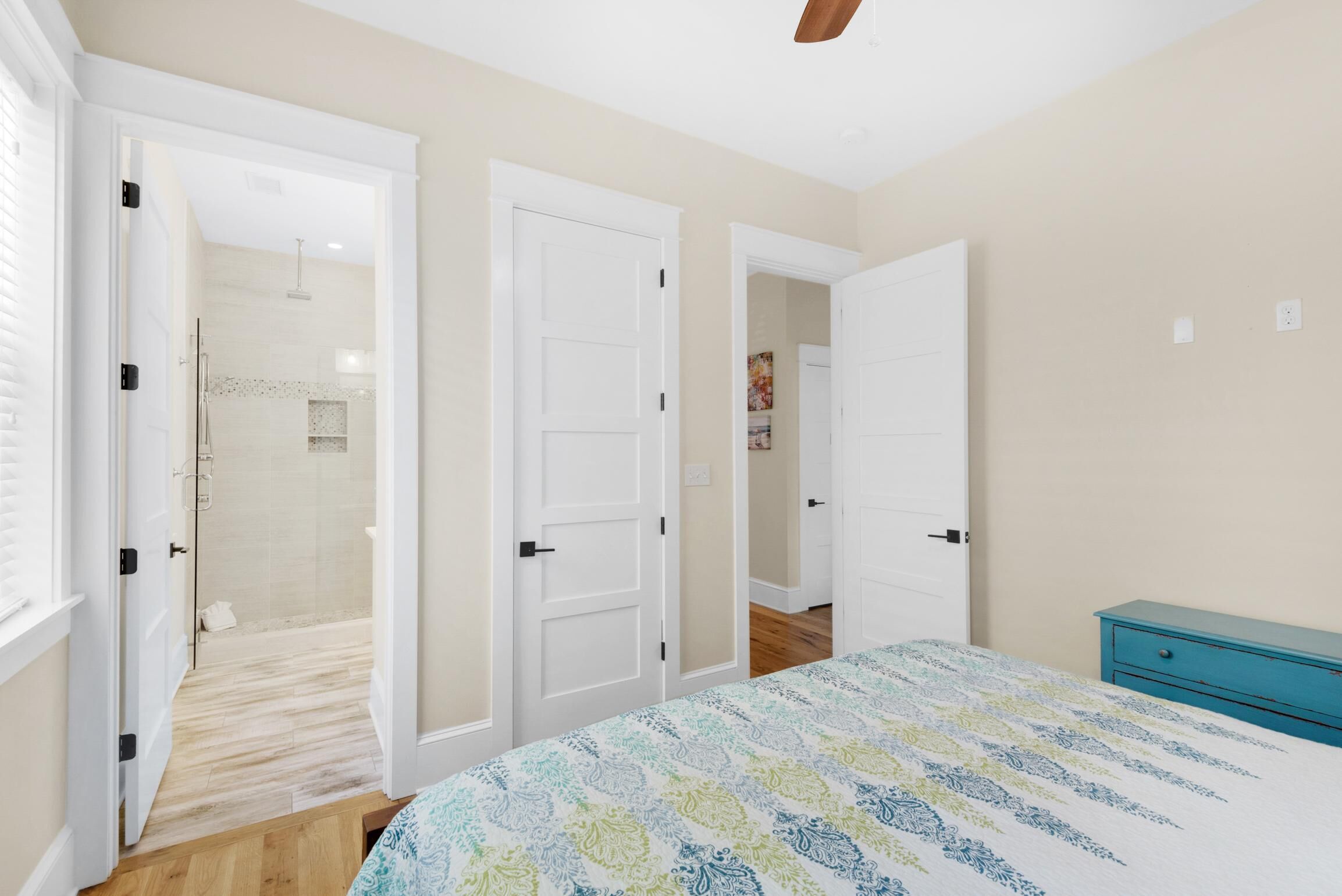 Un dormitorio con cama, cómoda azul y zona de ducha.