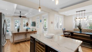 A spacious kitchen with a large island, wooden flooring, and a ceiling fan. - Calm Breeze Cottage (Santa Rosa Beach)