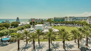 Un hotel sul lungomare con vista sull'oceano, palme e un'area di parcheggio.