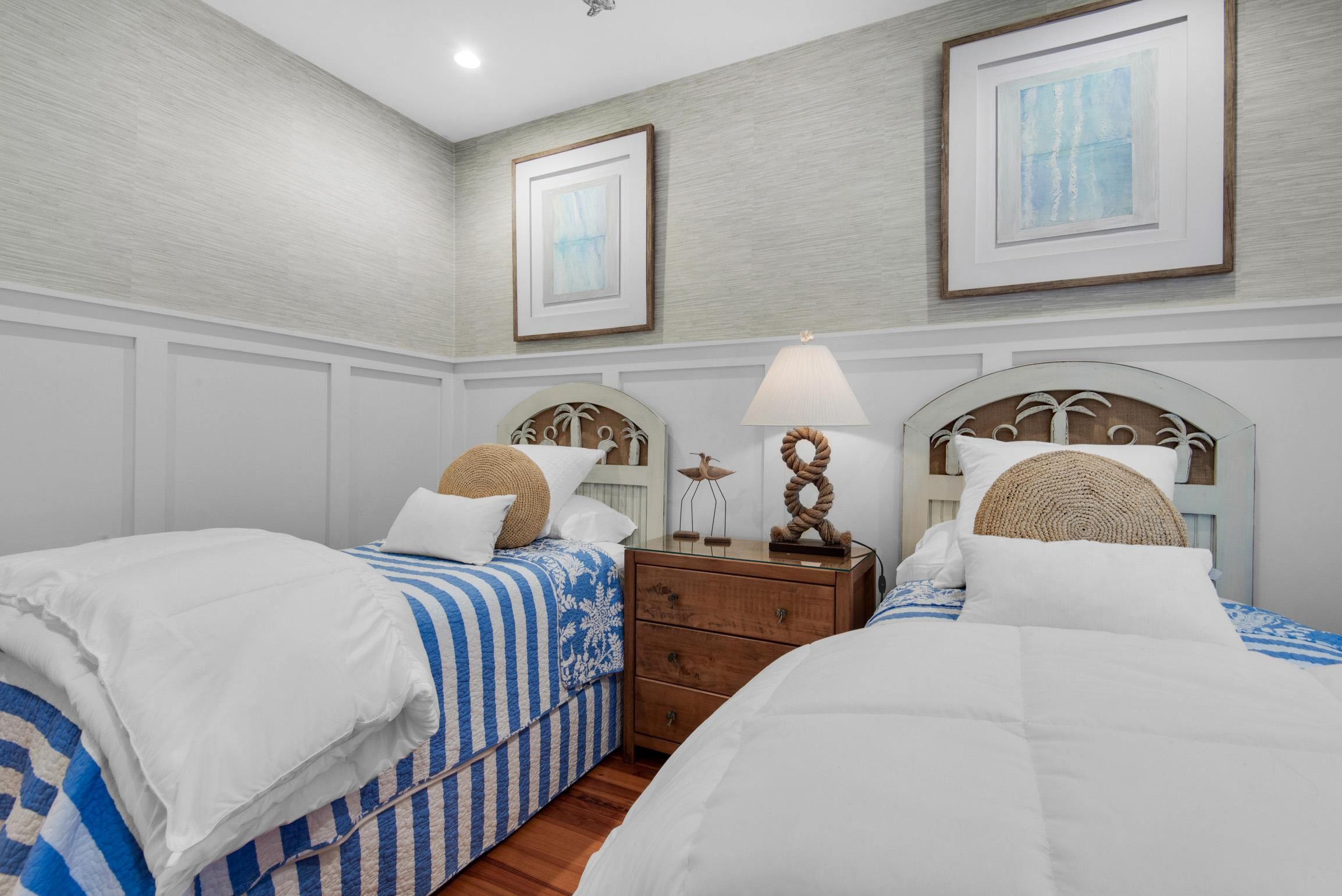 A hotel room with two beds, a wooden nightstand, and a lamp.