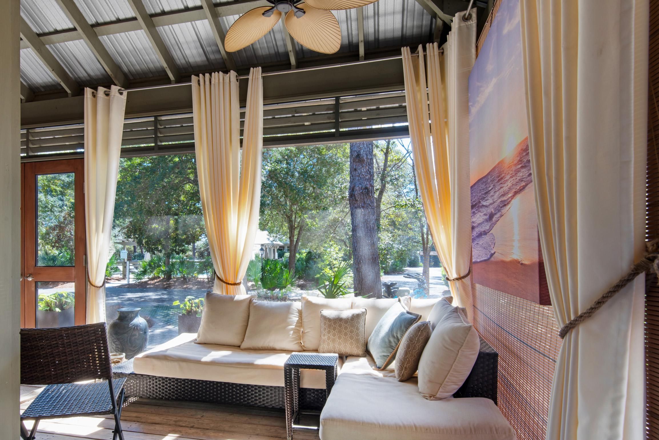 Una habitación con sofá, sillón y un ventanal con cortinas.