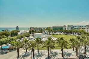A hotel with a pool area, palm trees, and a view of the ocean. - Bramble Cottage (Santa Rosa Beach)