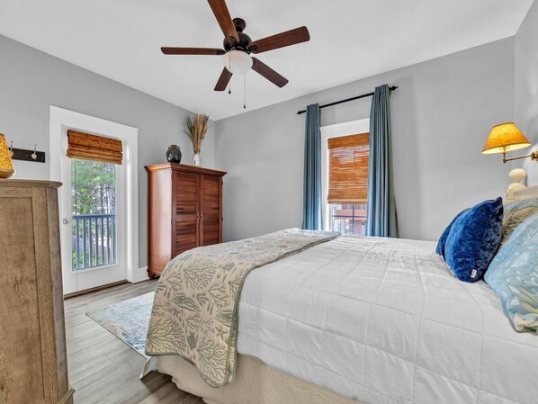 Cozy bedroom with a large bed, wooden dresser, and a window with blue curtains.