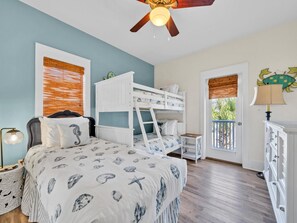 Relax in this cozy bedroom with a bunk bed setup, ceiling fan, and a window offering a view of lush greenery.