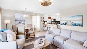 Un salon moderne comprenant un canapé, des fauteuils, une table à manger et un coin cuisine.