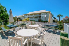 A deck with outdoor seating, including tables and chairs, overlooking a building with multiple balconies. - Beachside Villas 332 (Santa Rosa Beach)