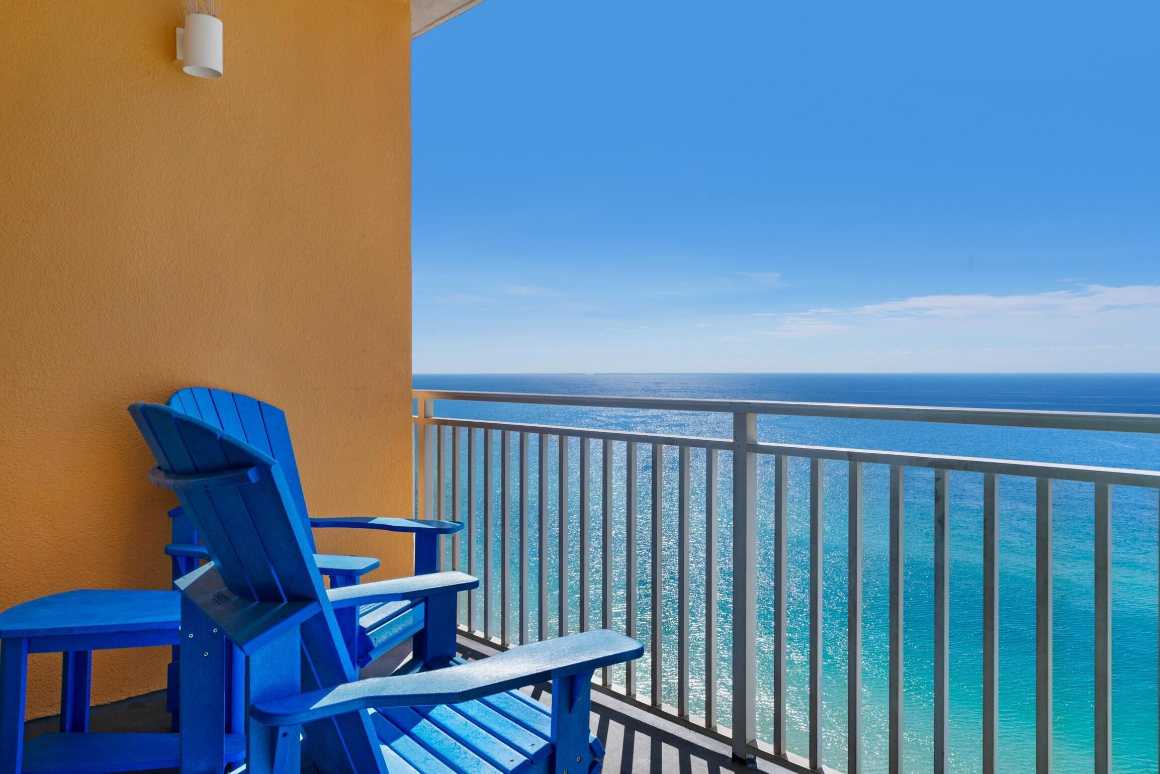 Ein Balkon mit blauen Adirondack-Stühlen und Blick auf den Ozean.