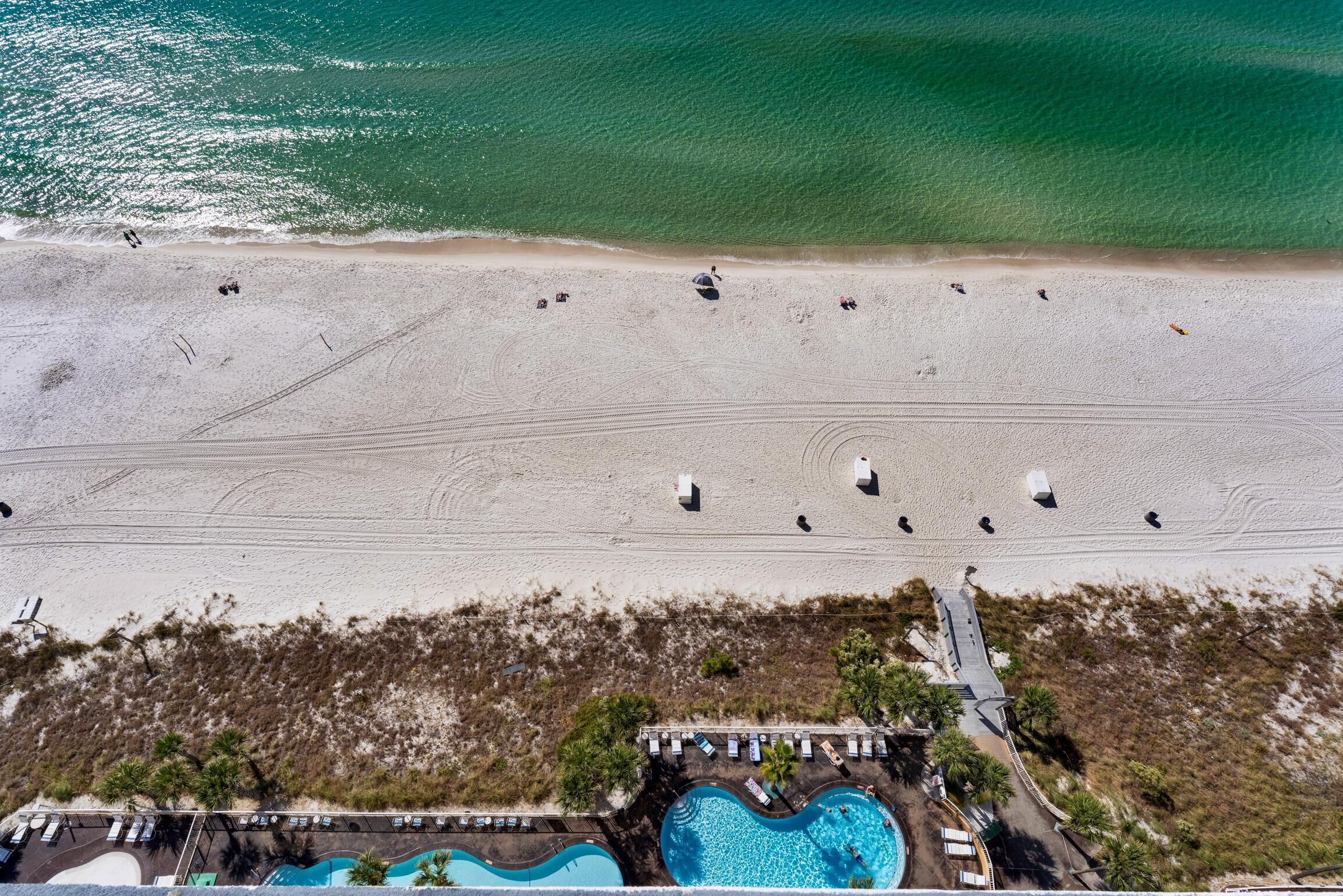 An aerial view of a beach with a swimming pool and lounge chairs.