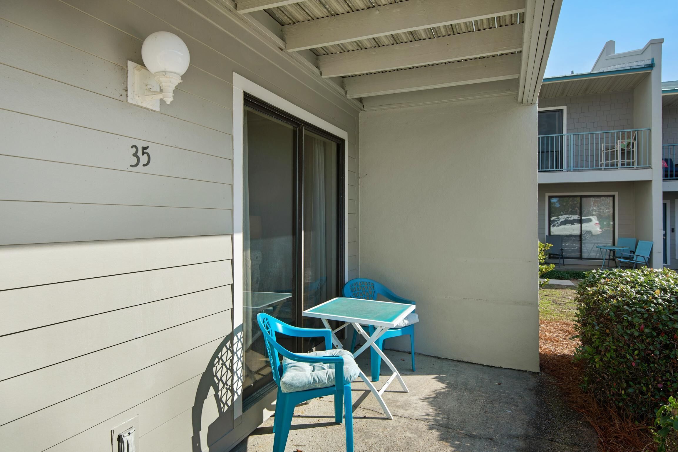 A balcony with a table and two chairs, a number '35' on the wall, and a view of another building.