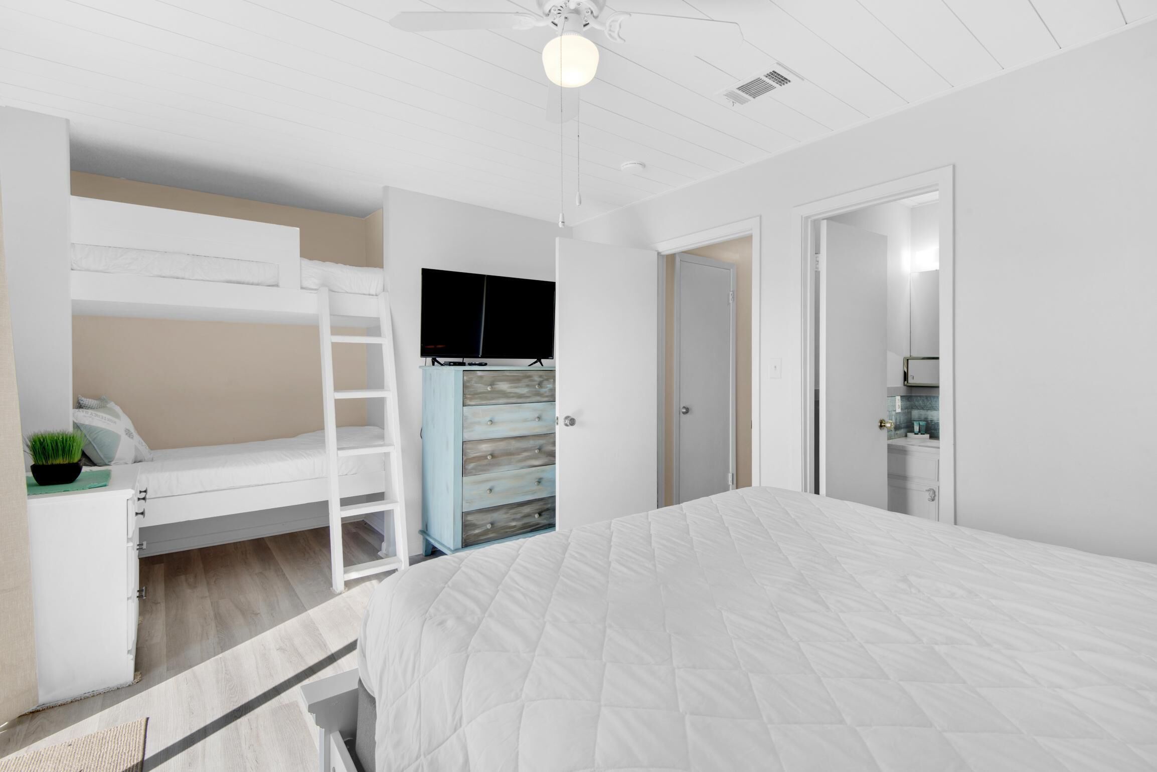 A bedroom with a bunk bed, a desk with a chair, a dresser, and a wardrobe.