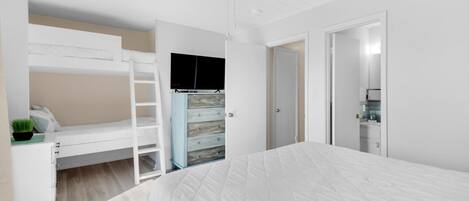 A bedroom with a bunk bed, a desk with a chair, a dresser, and a wardrobe.
