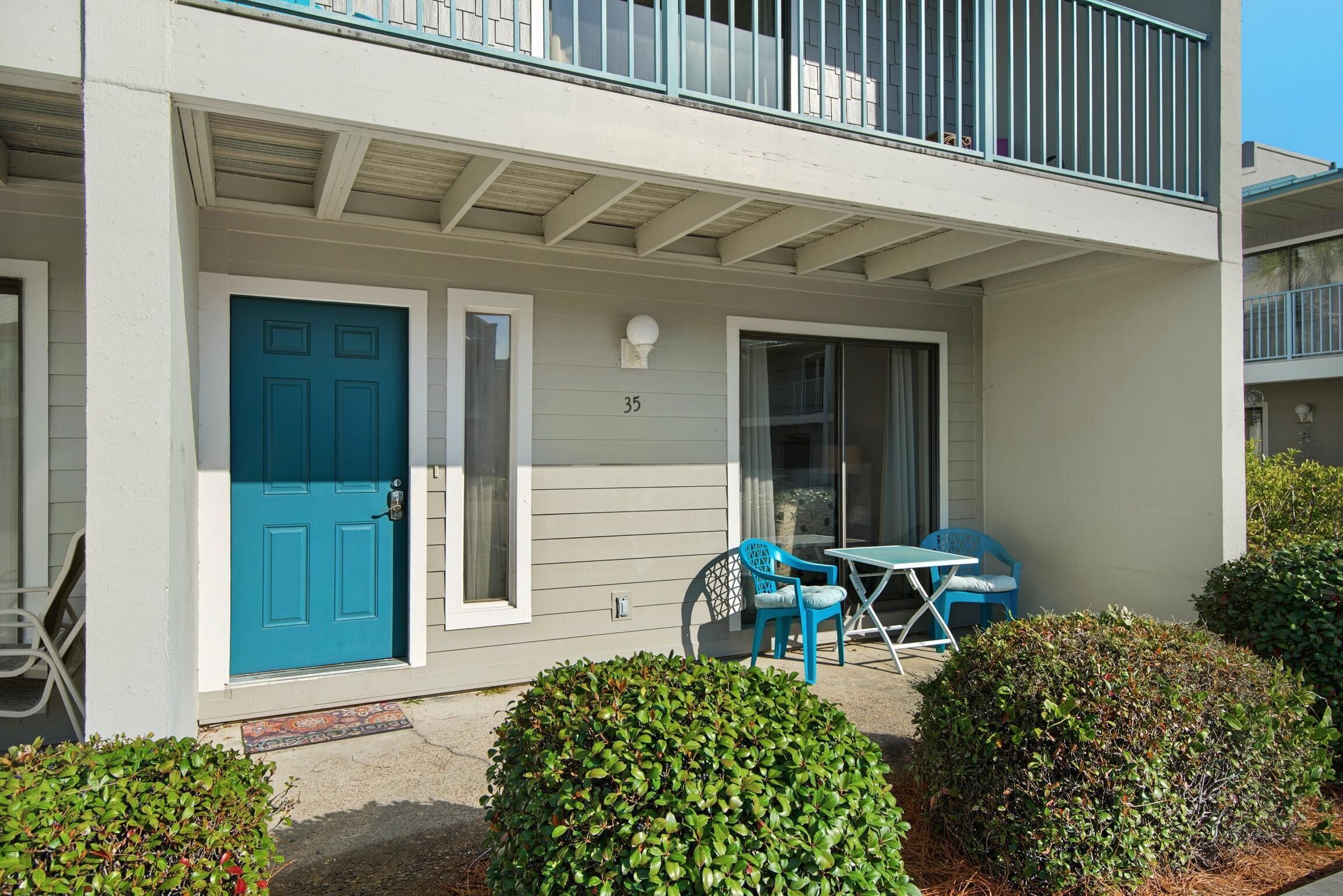 A two-story building with a blue door, number 35, and a balcony with a railing.