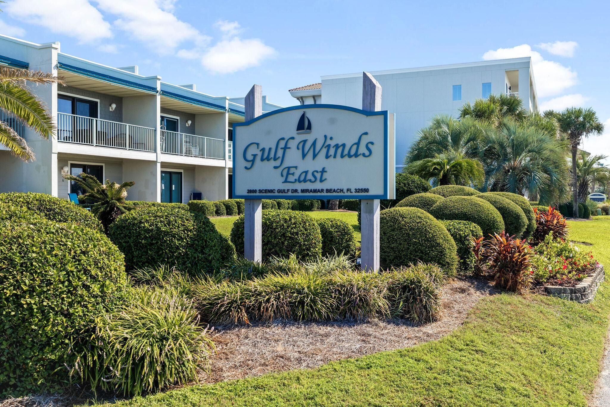 Señal de Gulf Winds East, un edificio con varios balcones y un jardín bien cuidado.