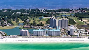 Un complesso alberghiero costiero con diversi edifici a più piani, spiaggia privata e vegetazione circostante.