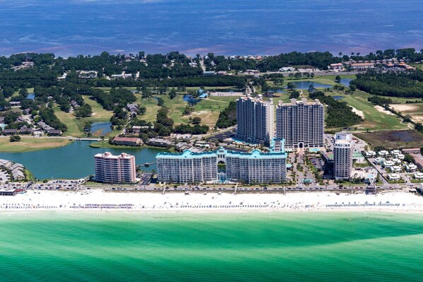A coastal hotel complex with multiple high-rise buildings, a beachfront, and surrounding greenery.