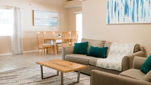 A living room with a sofa, coffee table, and a painting on the wall. - Cozy Home 20 min to Beach! Private Backyard. Pet Friendly (Fort Myers)