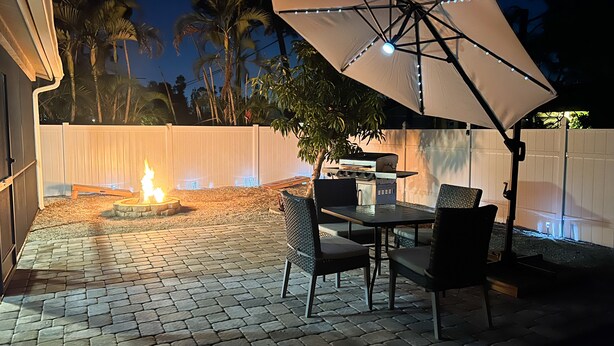 An outdoor patio with a fire pit, a grill, and a table with chairs. - Cozy Home 20 min to Beach! Private Backyard. Pet Friendly (Fort Myers)