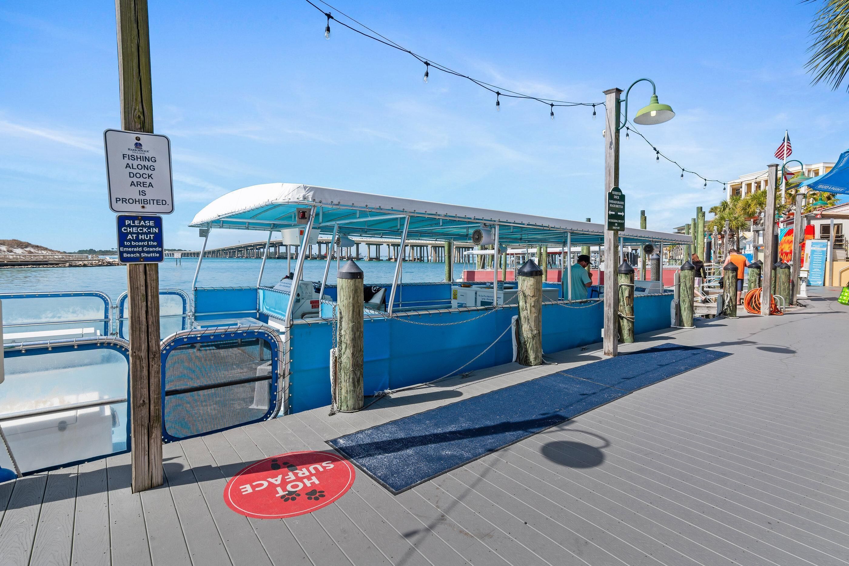 A docked boat, a sign prohibiting fishing, a blue awning, and a wooden walkway.