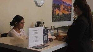 Una zona de recepción con un reloj, un cuadro de paisaje enmarco y un mostrador de recepción con un cartel.