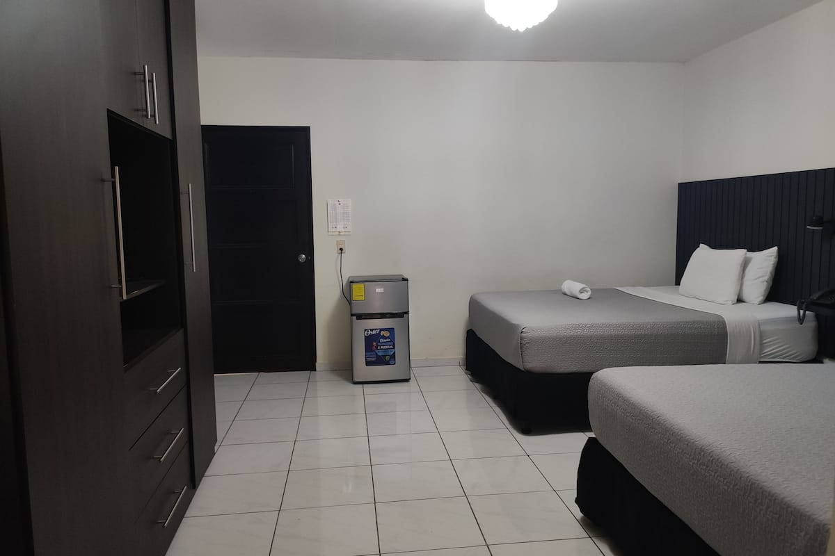 Habitación de hotel con dos camas, minibar, escritorio y armario.