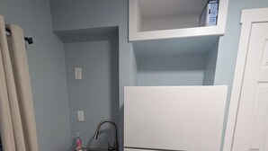 Una cocina compacta con un lavamanos, un refrigerador blanco y un estante pequeño.