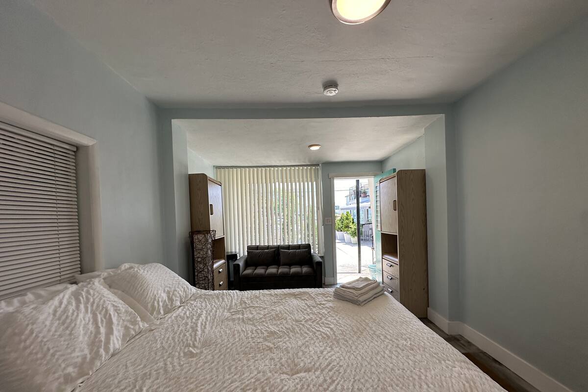 A bedroom with a large bed, a sofa, and a wardrobe.