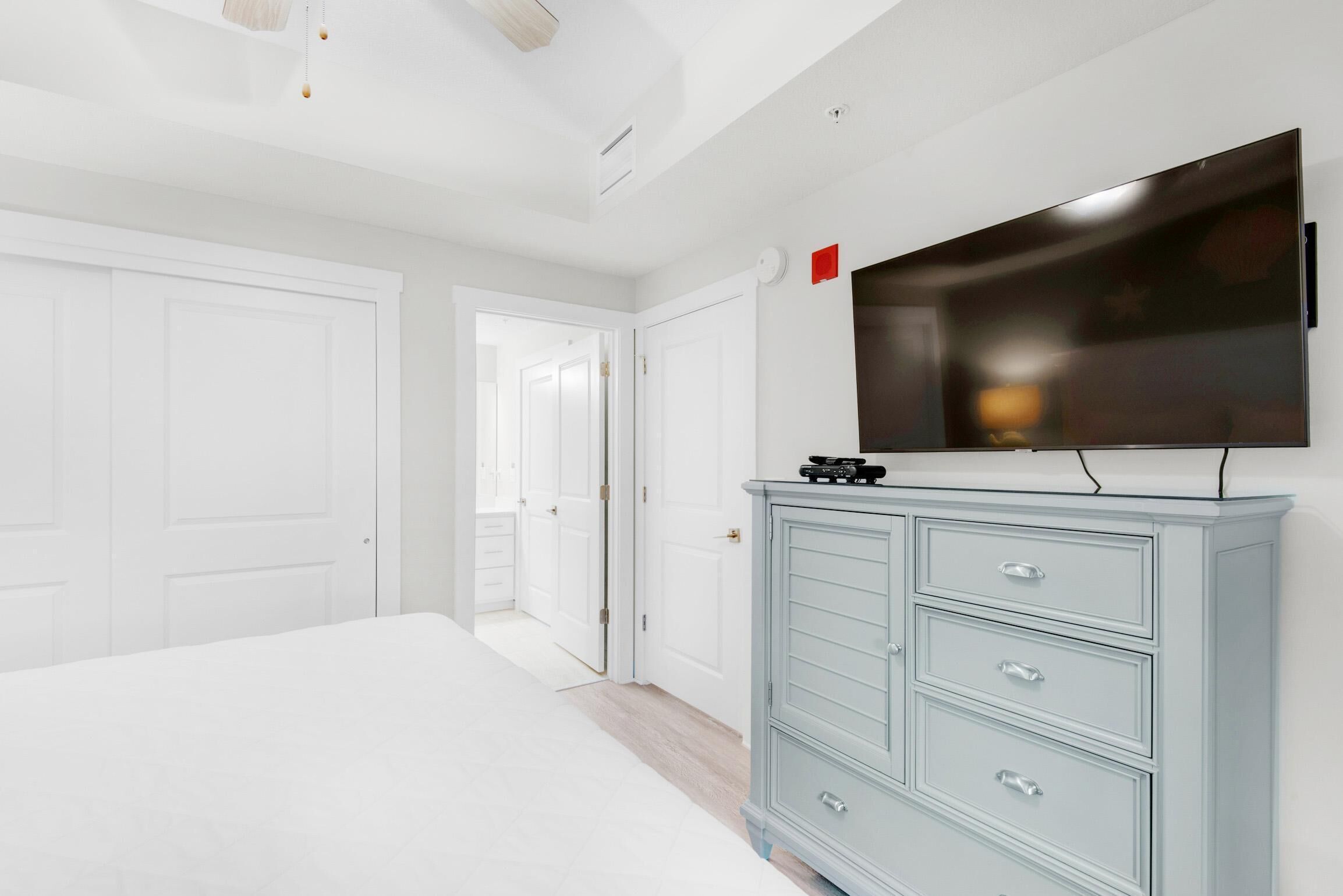 A bedroom with a bed, a dresser, and a TV mounted on the wall.