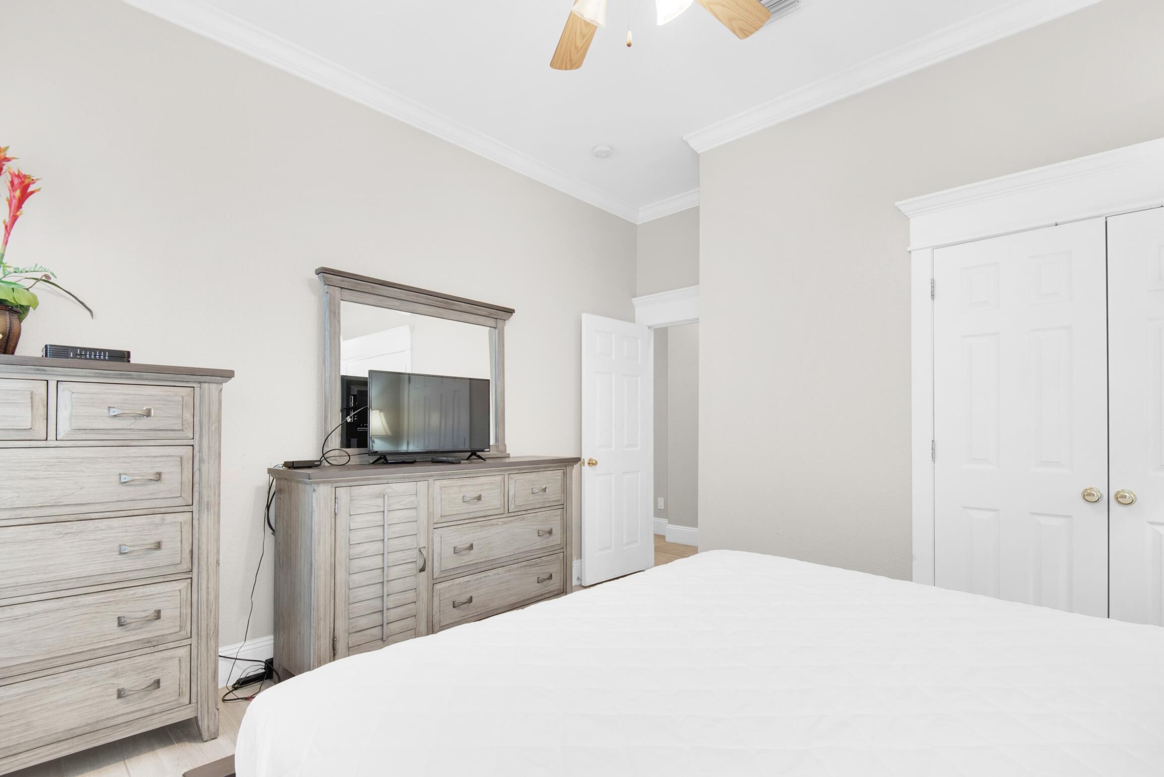 Une chambre à coucher avec un lit, une commode, un téléviseur et une porte.