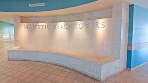 A reception desk with the sign "MAJESTIC BEACH TOWERS" in a modern lobby with tiled flooring and curved ceiling design. - Majestic Beach Towers 1-2314 (Panama City Beach)