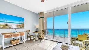 A balcony with a view of the ocean, a wooden table, a sofa, and a desk with chairs. - Majestic Beach Towers 1-2314 (Panama City Beach)