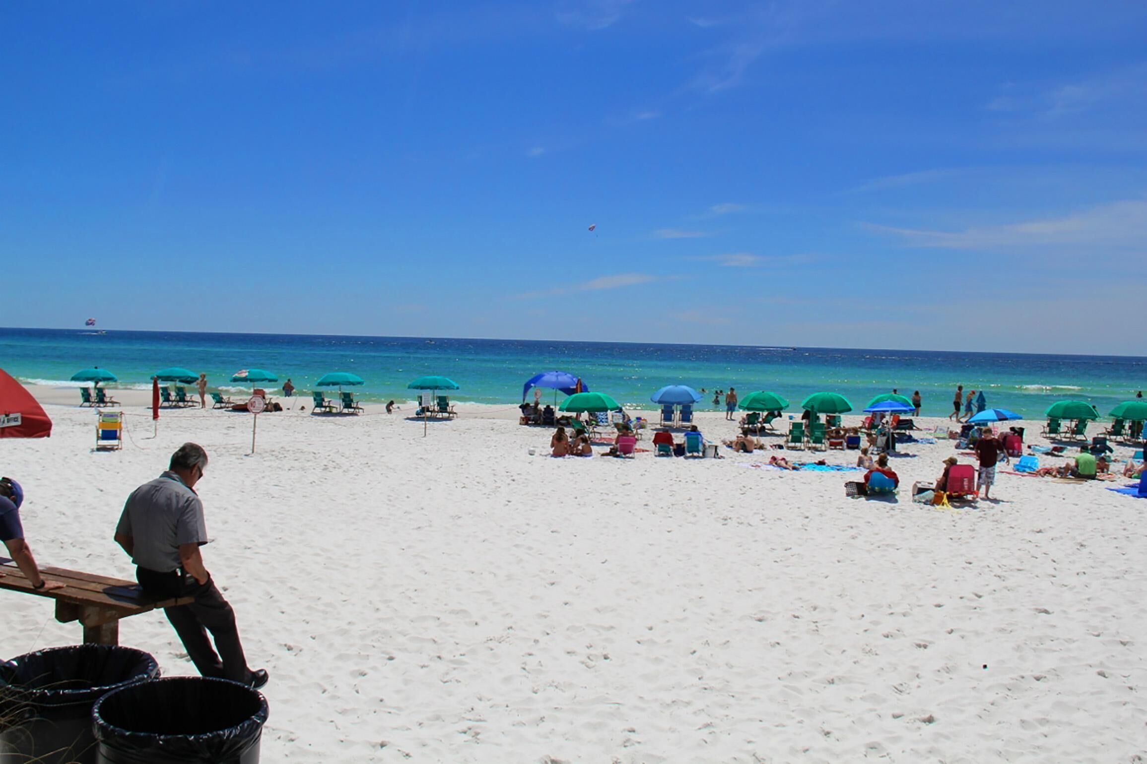 Una playa con numerosos paraguas y gente relajándose.