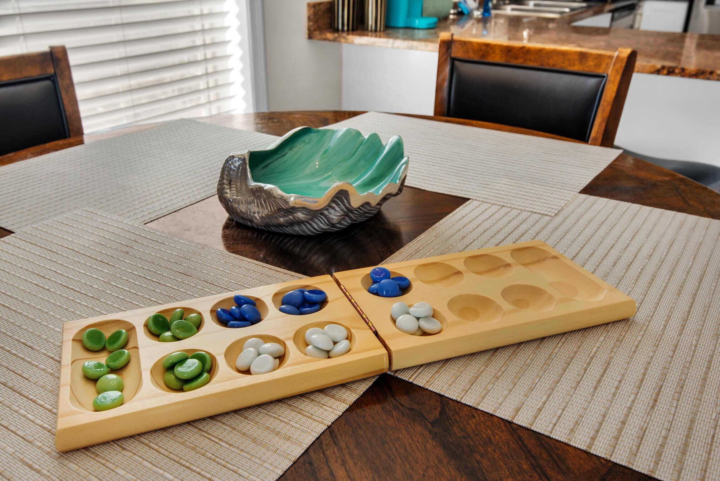 Ein Holz-Brettspiel mit grünen und weißen Figuren auf einem Tisch mit einer gewebten Unterlage.