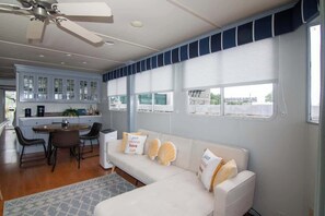 A modern interior with a white sofa, a dining table with chairs, and a kitchen area.