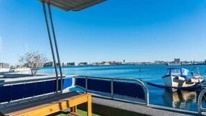A waterfront view with a docked boat, a wooden bench, and a clear blue sky.