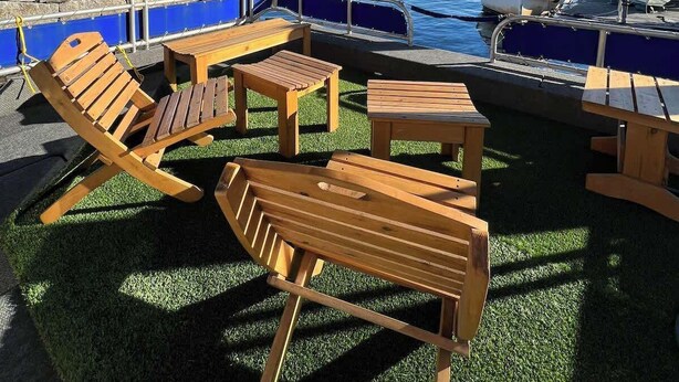 An outdoor seating area with wooden furniture, a ceiling fan, and a view of the water and boats. - Paradise Found: Luxury Roof Deck (Boston)