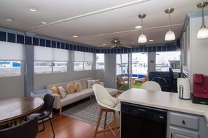 A modern kitchen with a dining area, a sofa, and a view of the marina.
