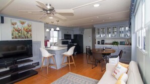 A modern living room with a TV, seating, a dining area, and a kitchen. - Paradise Found: Luxury Roof Deck (Boston)