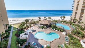 A resort with a pool area, lounge chairs, and a view of the beach.