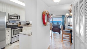 A kitchen with white cabinets, stainless steel appliances, and a dining area with wicker chairs.