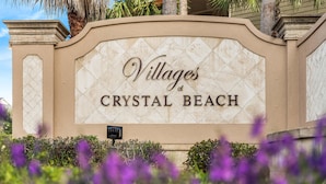 A sign for "Villages of Crystal Beach" with a decorative arch and a security camera. - Sea Sprite (Destin)
